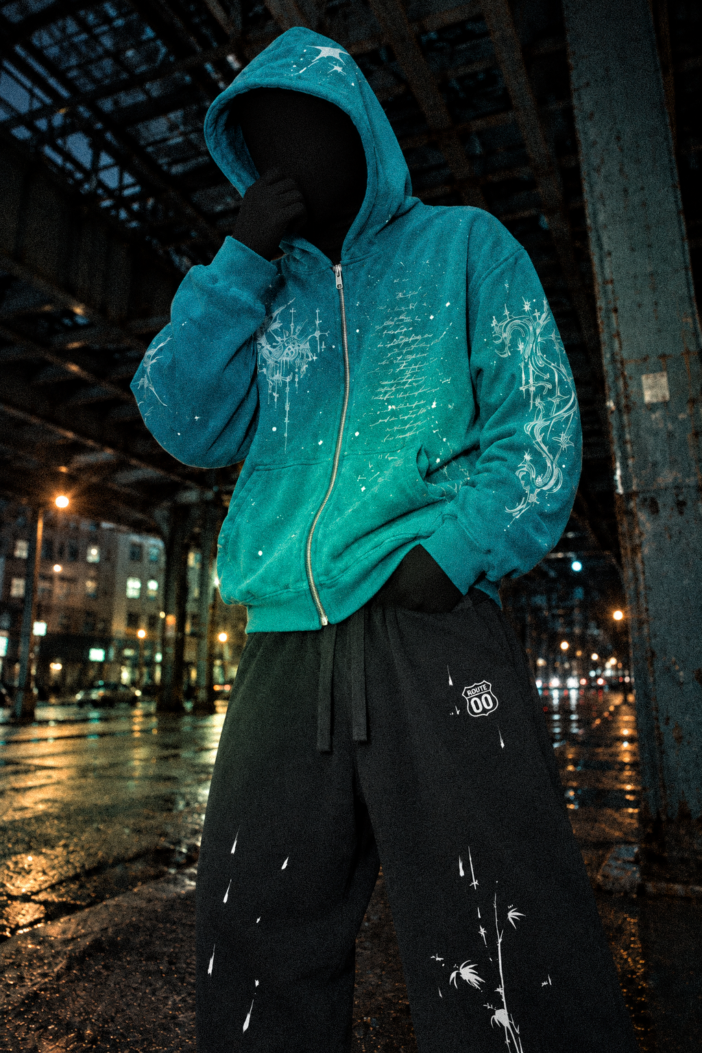Look 007 — Blue Hour hoodie and Route 00 sweatpants, anonymous night portrait beneath an industrial structure.