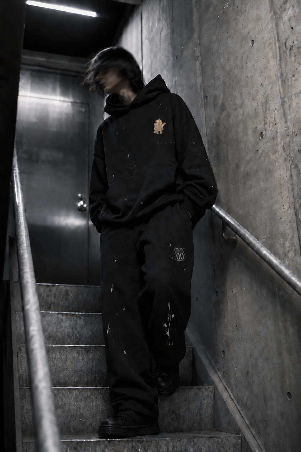 Black oversized graphic hoodie in a concrete stairwell